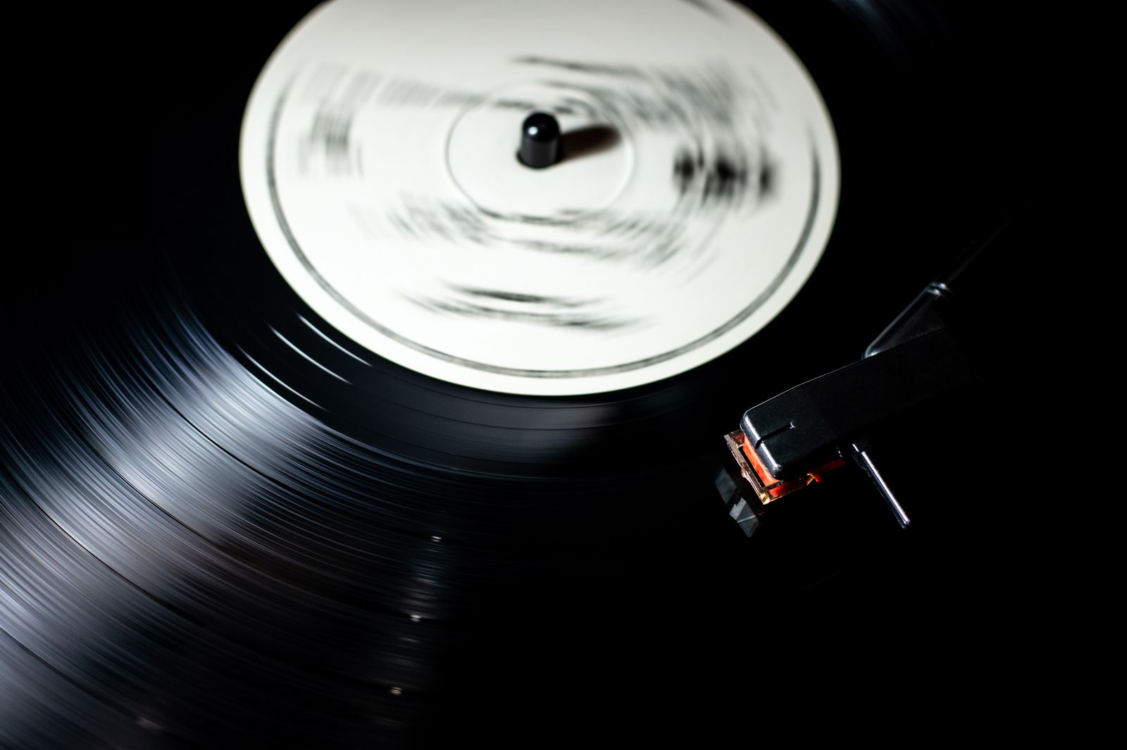 A vinyl record playing on a turntable in a dimly lit room